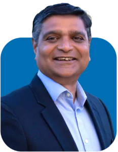 Headshot of a smiling man wearing a dark blazer and light blue shirt, against a bright blue background.